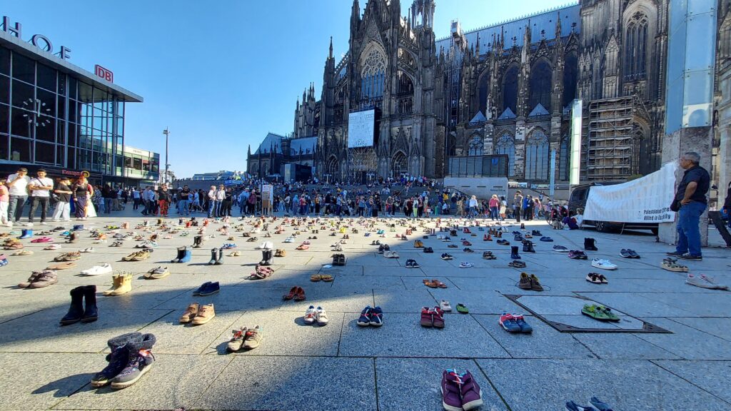 Platz vor dem HBF mit Kinderschuhen und Zuschauern, der Dom im Hintergrund